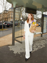 A lady wears a white linen blazer.